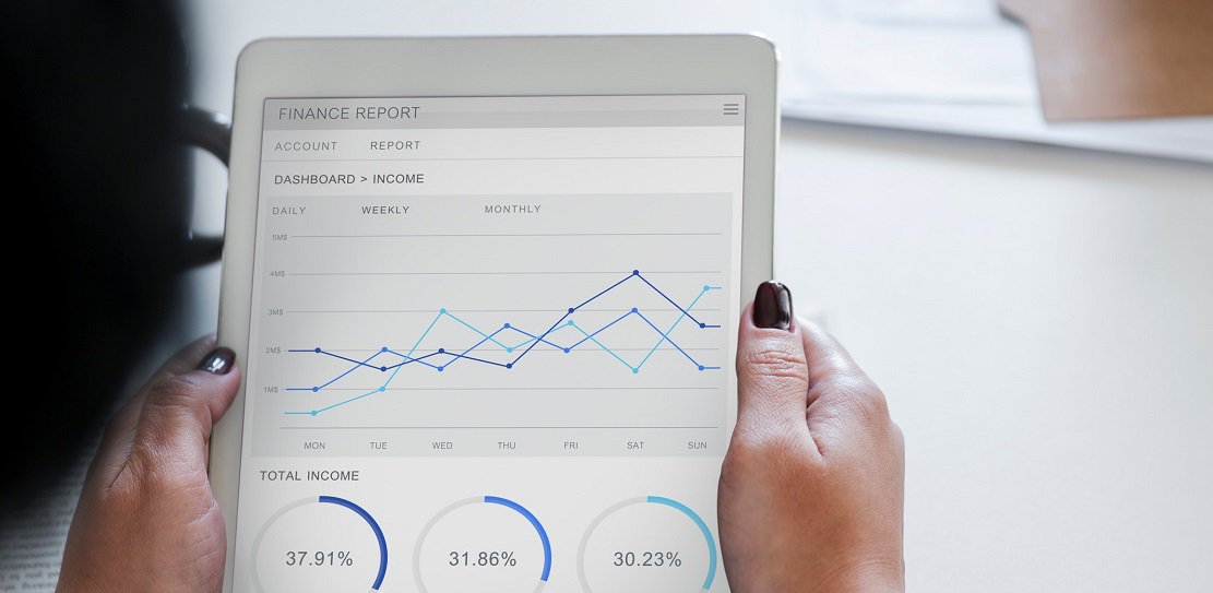 Closeup over shoulder of woman looking at financial report of gym revenue on tablet device
