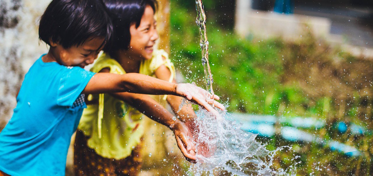 Kids laughing, playing in water at outdoor summer camp
