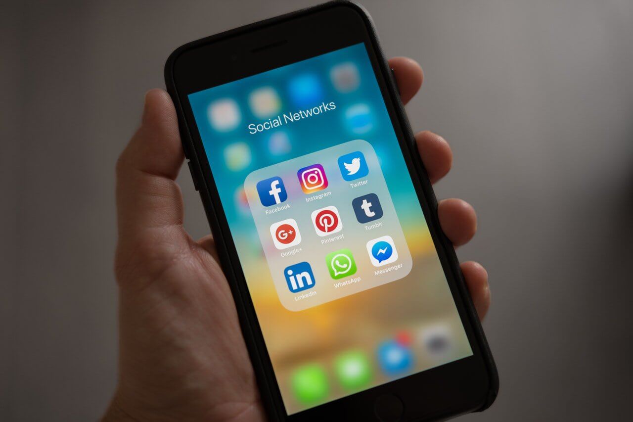 hand holding mobile device with social media icons
